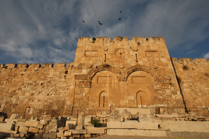 Birds fly over the golden gate walls as the sunrises over the old city of jerusalem